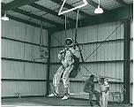 A-12 Pilot Ken Collins hanging above base pool prior to dunking. Capt Trapp on diving board with Capt. Cravada's suit tech, name unknown
